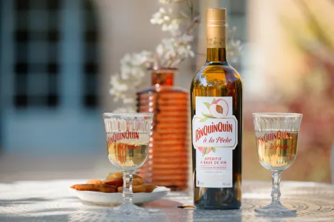 Liqueur à la pêche servie en apéritif sur une table au soleil