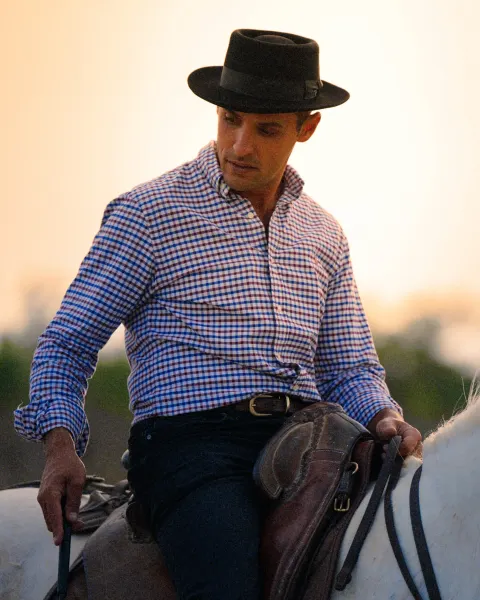 Gardian à cheval en Camargue au soleil couchant, chapeau noir et chemise à carreaux