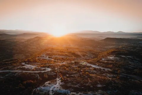 Soleil couchant sur les collines et la garrigue, vue aérienne d'une route sinueuse